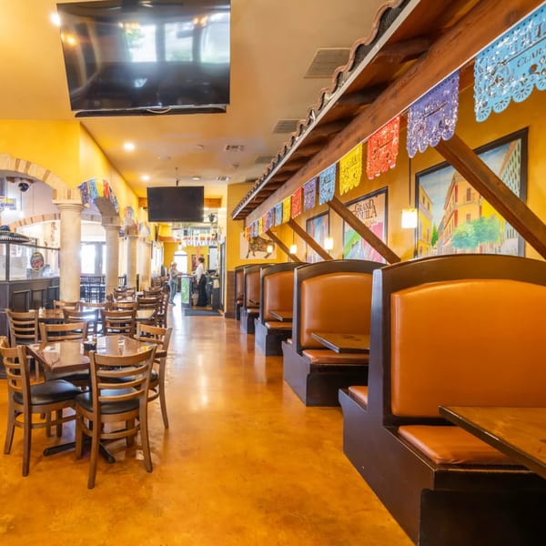 Interior of Grand Tequila Mexican Restaurant with colorful papel picado, booths, tables, and bar area.
