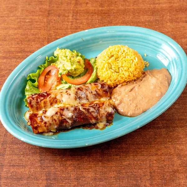 Two cheesy enchiladas with rice, refried beans, guacamole, and salad on a blue plate.