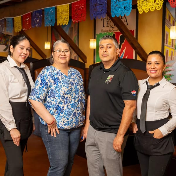 Four Grand Tequila Mexican Restaurant staff members, two men and two women, smiling in the dining area.